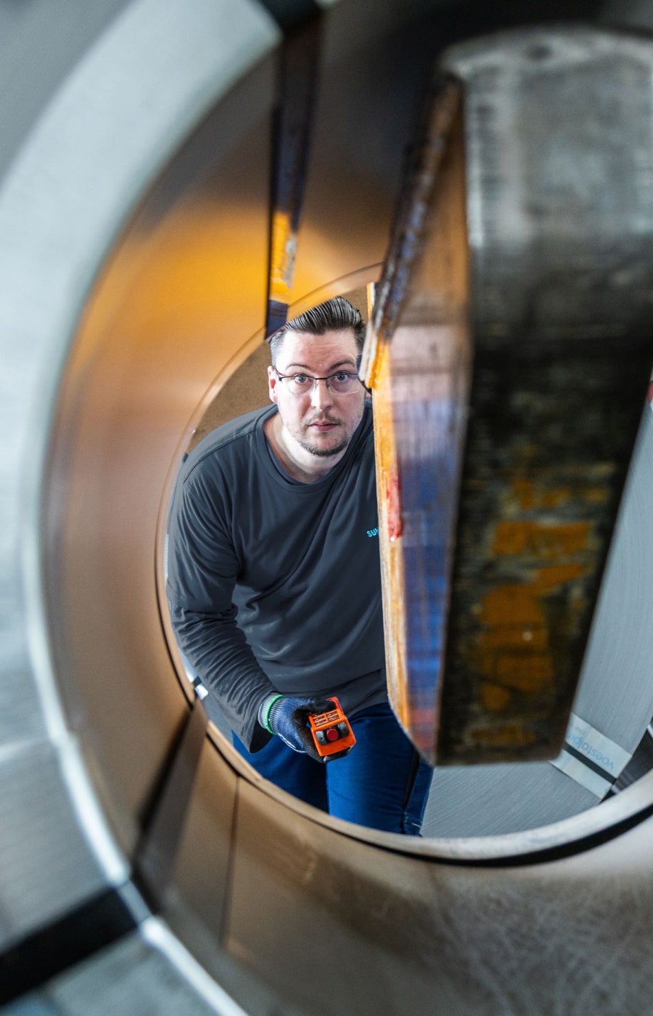 Ein Mitarbeiter von Sungwoo Hightech blickt durch einen großen Stahl-Coil und prüft das Material.